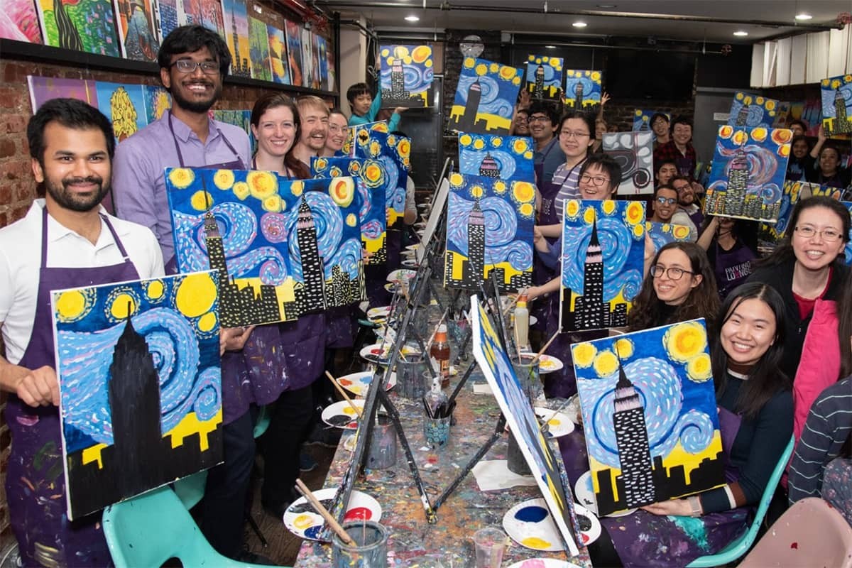 Group of Doctoral Students holding paintings during a fun activity