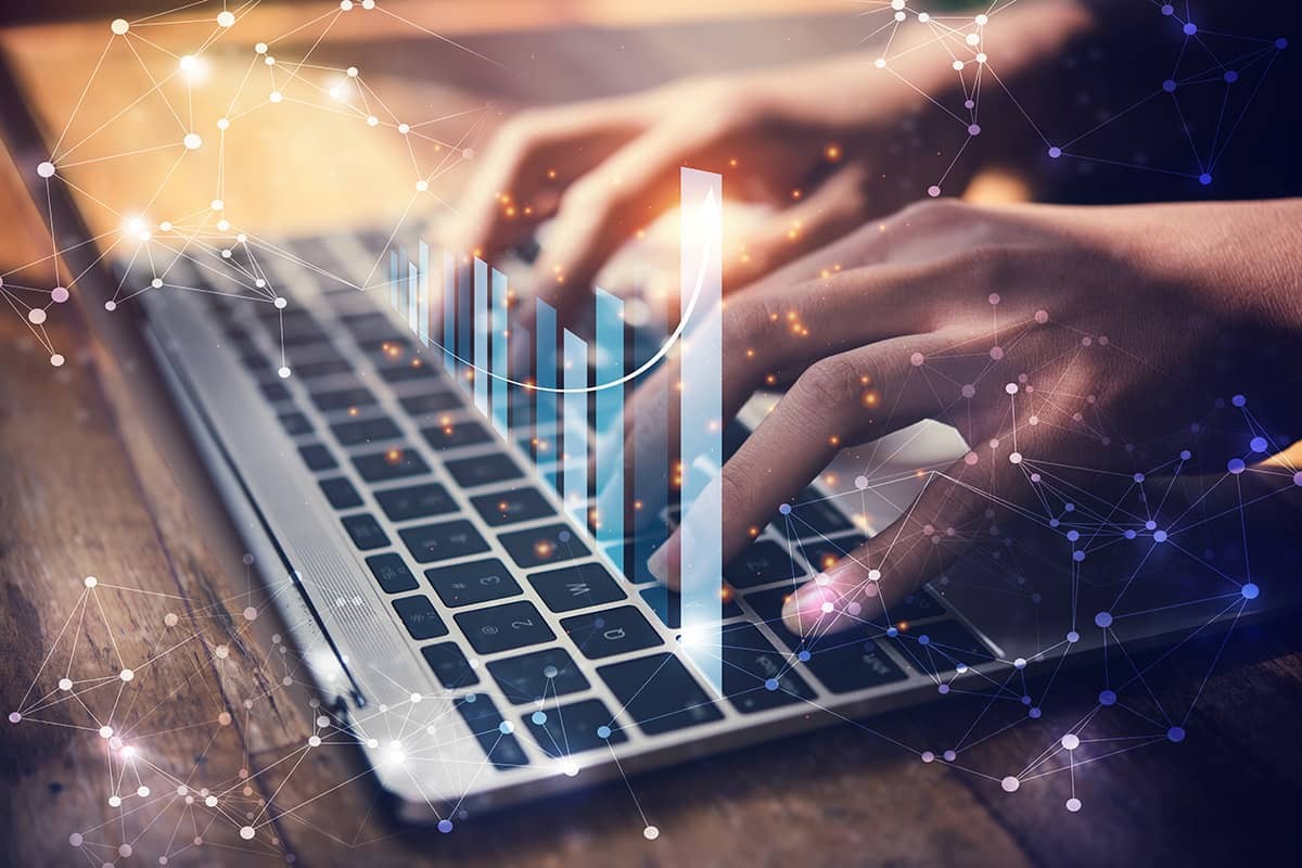 A person typing on a laptop with a bar chart emerging representing a Business Analytics student analyzing data at Columbia University