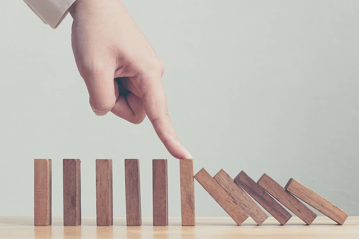 A hand pushing a wooden block up to the top of a row of block symbolizing advancing in the field of Financial Engineering and Risk Management 