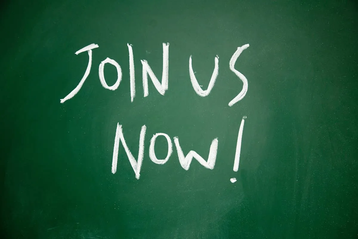 The phrase 'Join Us Now!' on a green chalkboard background