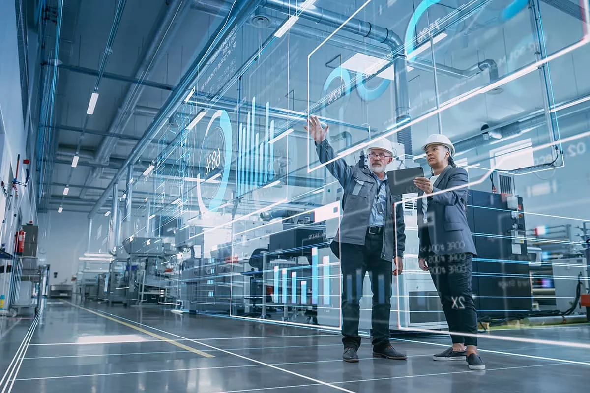 Two people in a factory examining projected data