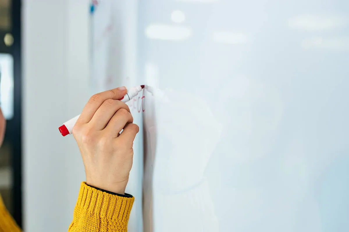 A person writing on a white board with a marker